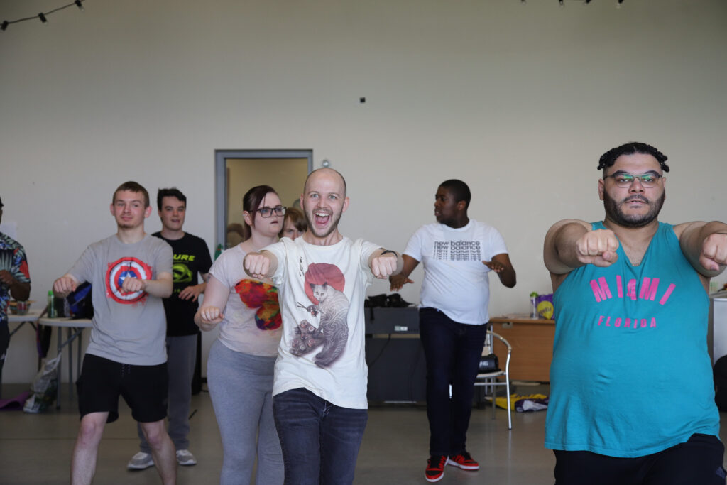 A photograph of group of people doing rehearsal with one guy having a big smile.
