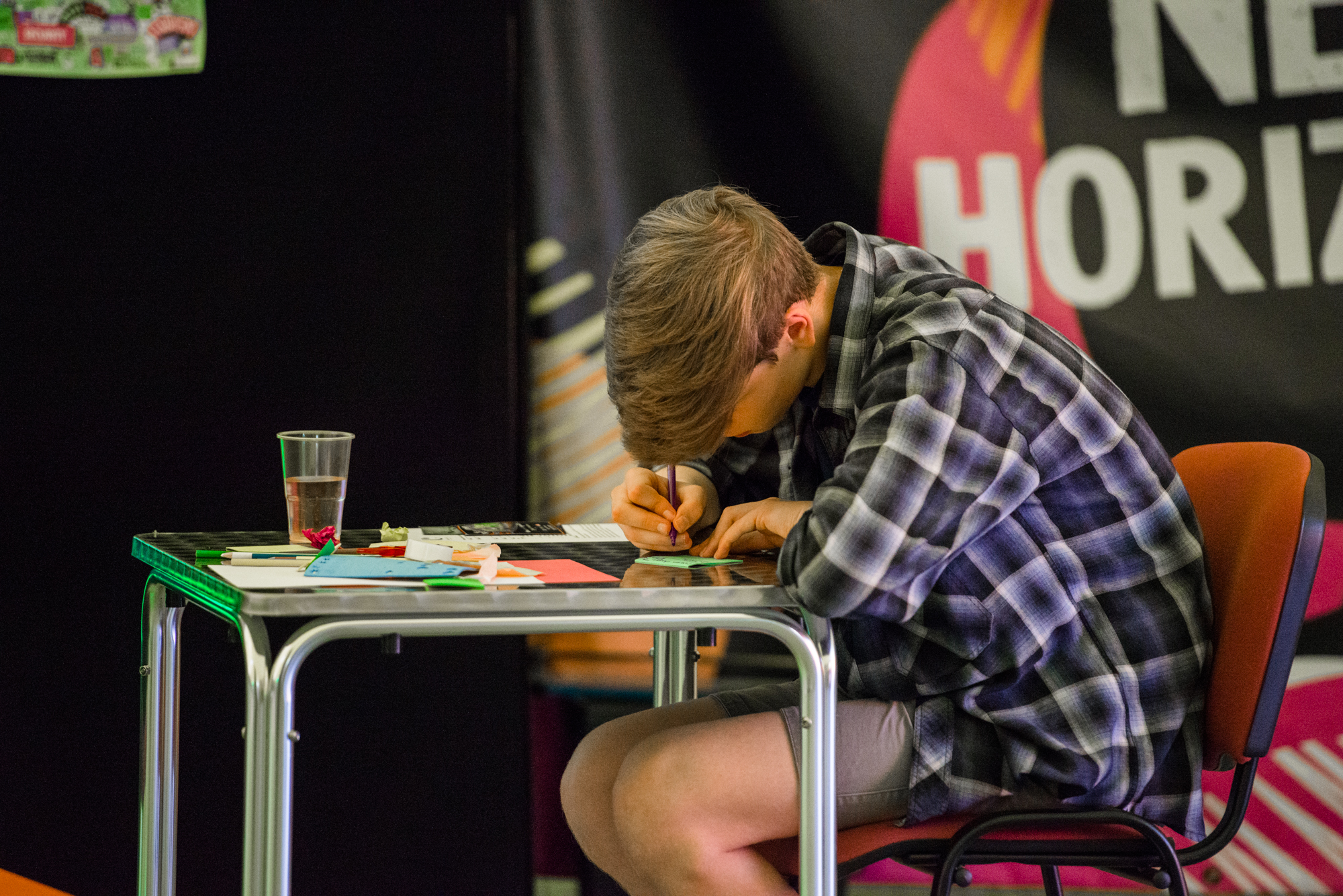 Photo of a young person, hunched over as he writes on a desk.