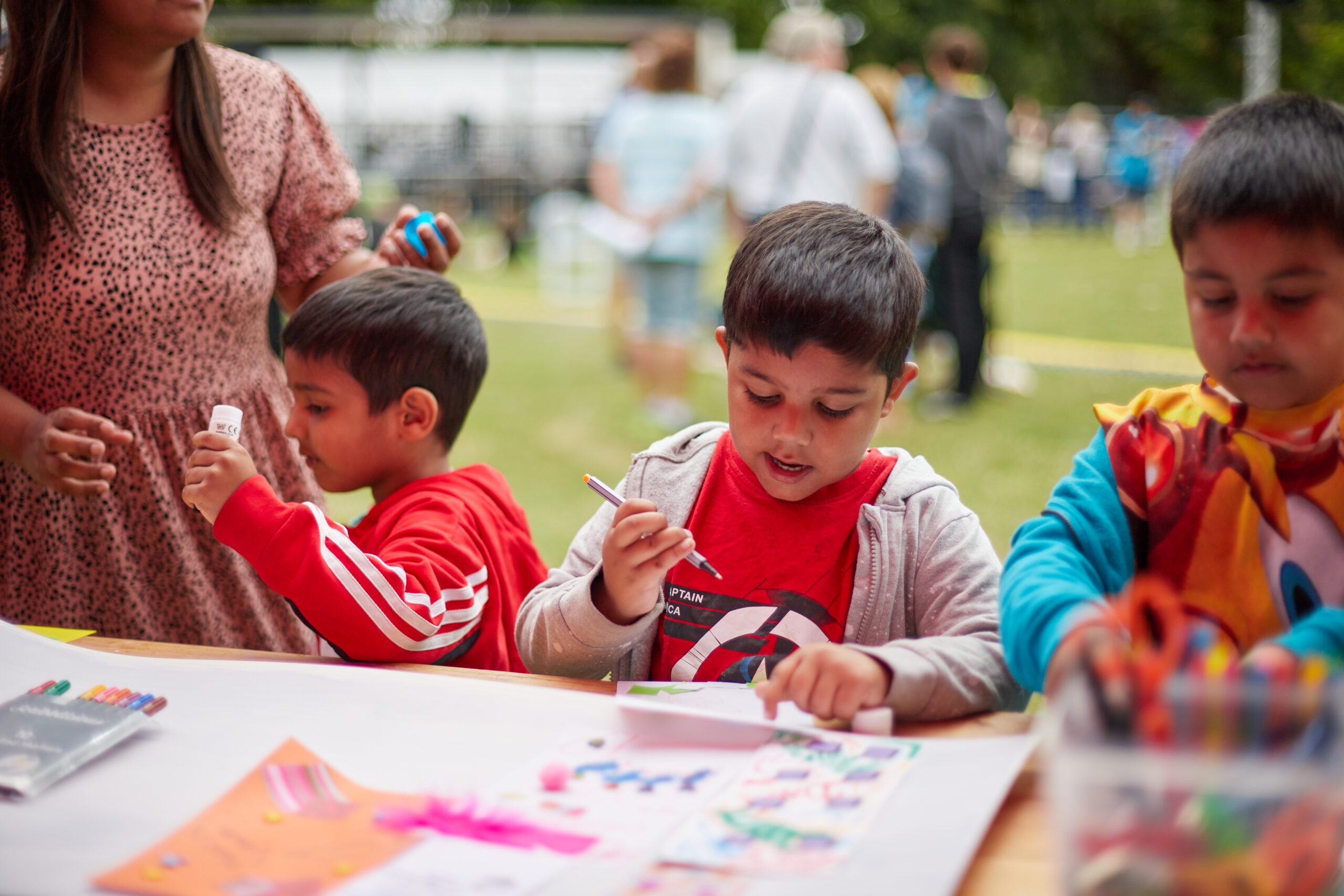 Photograph of children outside on a stall, drawing and playing.