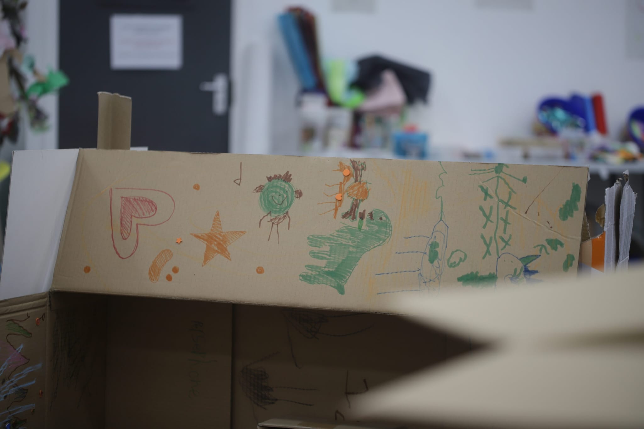Photo of a cardboard box - covered in children's doodles of dinosaurs and stars