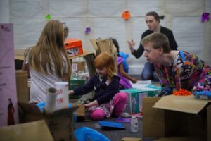 Photo of parent helping daughters craft in a pile of cardboard