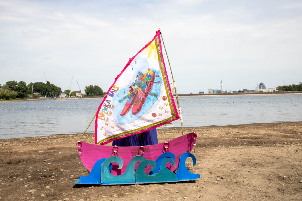 an image of a hand made cardboard boat outdoor in front of water.